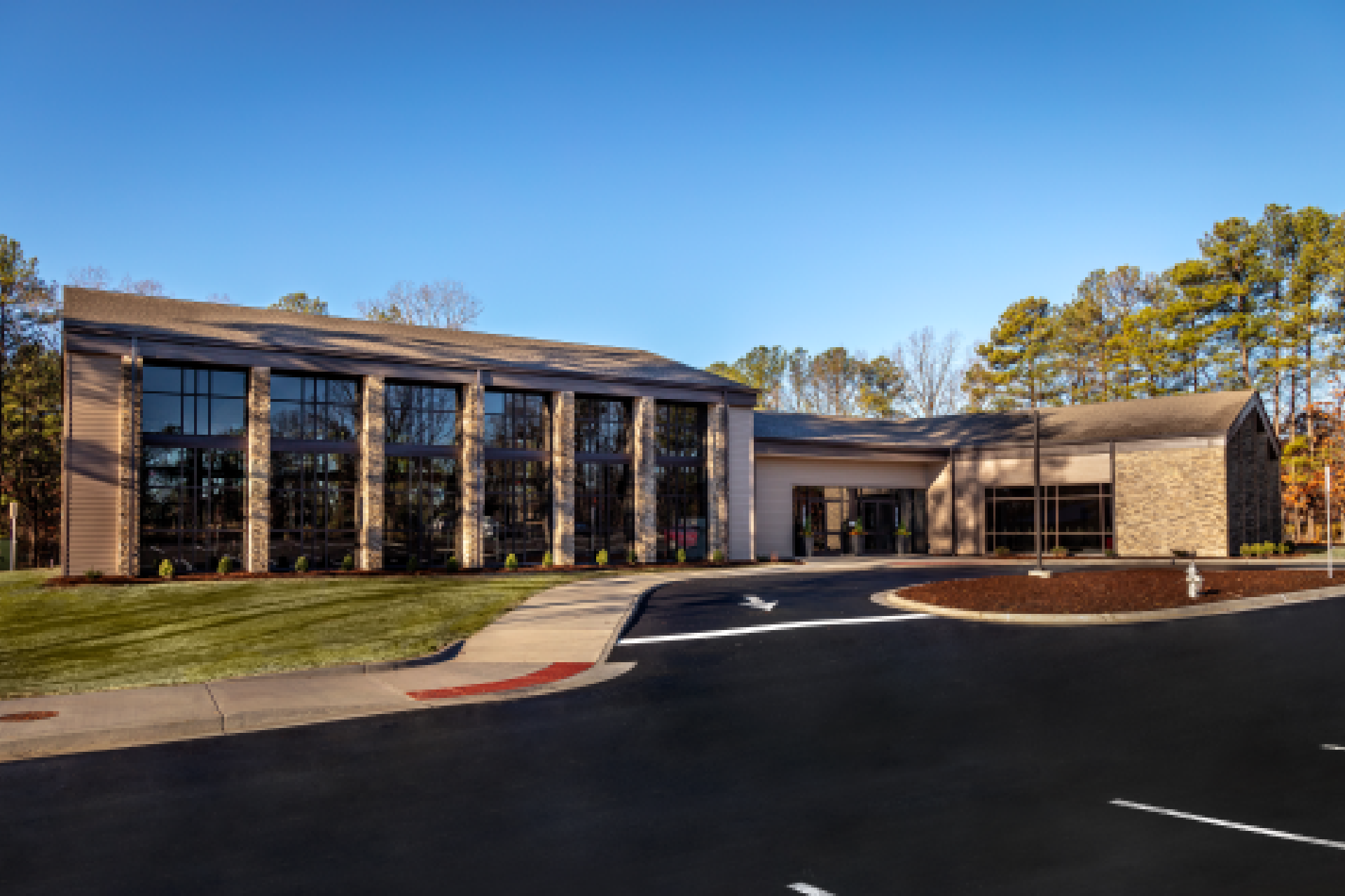 Aerial view of a modern suburban building with gray roofing and stone accents, surrounded by a parking lot